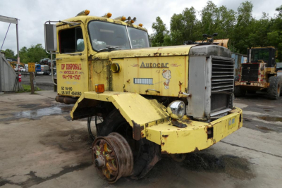 1973 Autocar cab cutaway showing front grille and missing front wheel with yellow paint and stock number decals.