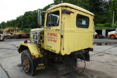 Autocar day cab truck cab cut showing yellow exterior with DP Disposal signage on door, front wheel, and rear section visible.