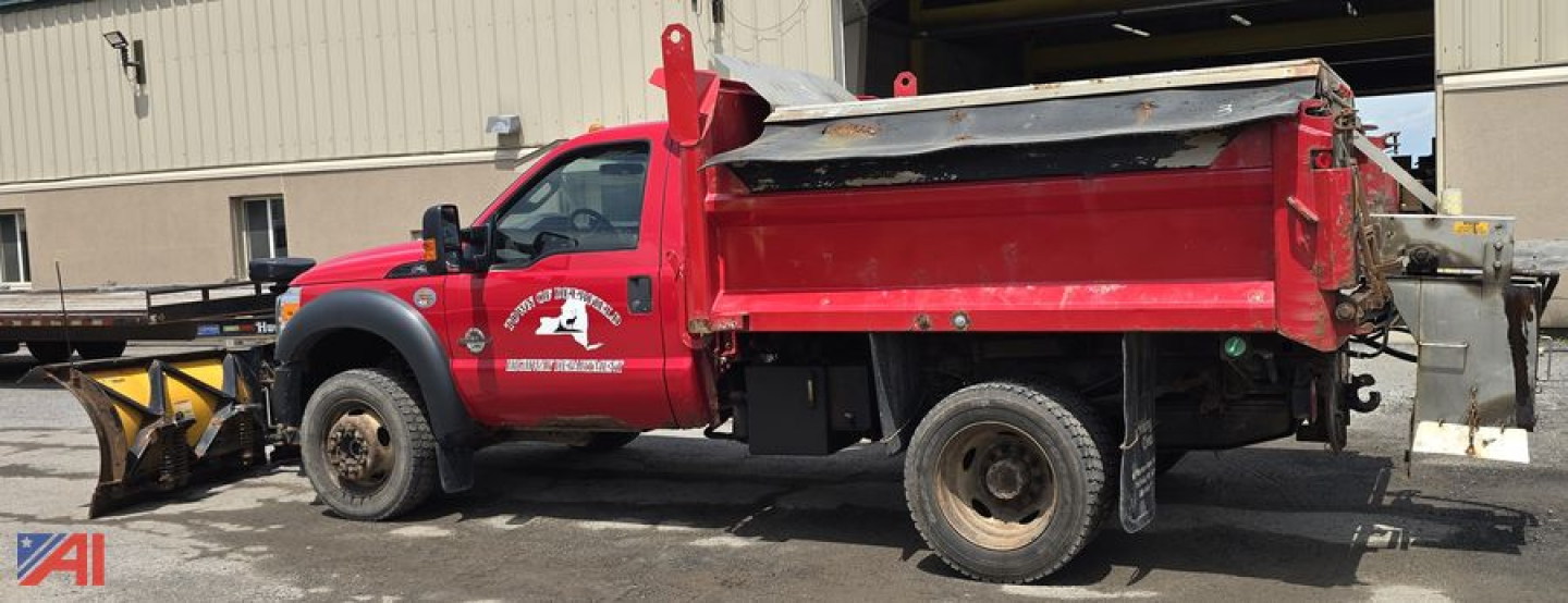 Ford F-550 dump/salt truck with plow in service showing red dump bed and side branding.