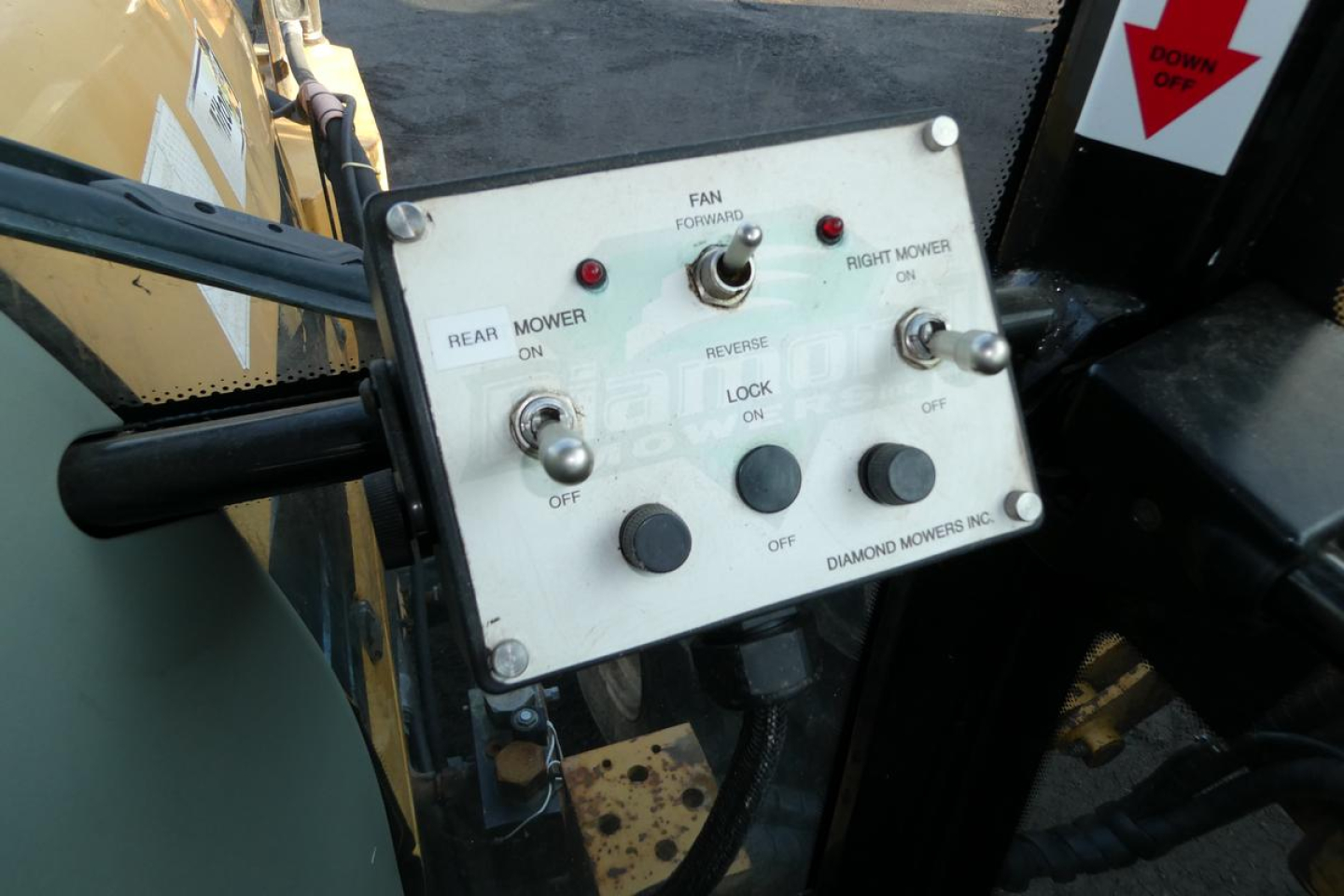 Tractor cabin control panel with labeled switches and indicator lights showing rear wiper, mower, forward direction, and diamond mowers inc. branding.