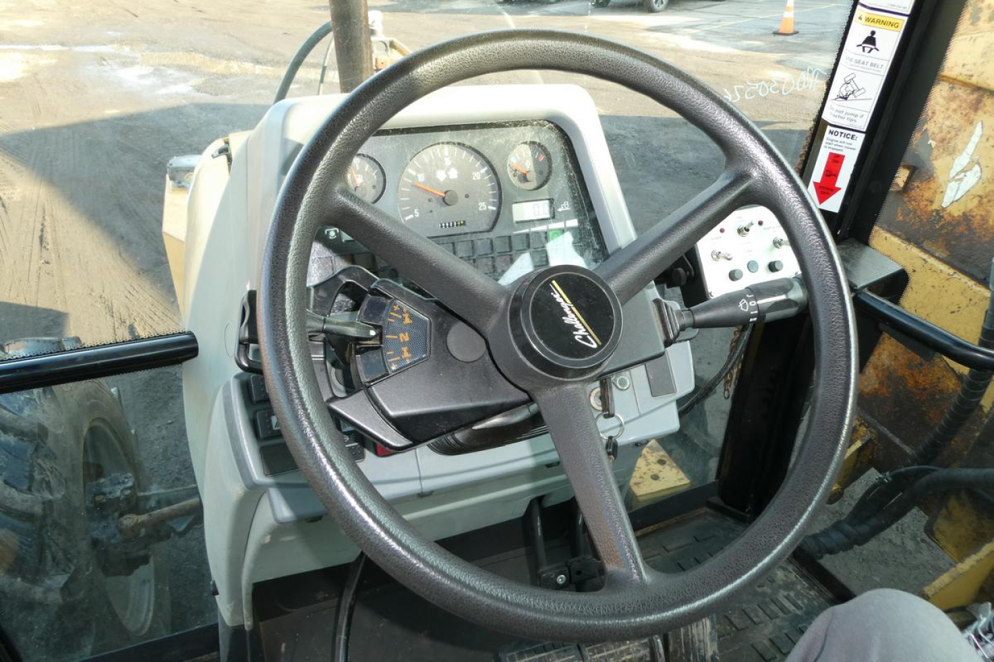 Steering wheel and instrument cluster inside Challenger MT455B cab showing dashboard gauges and controls.