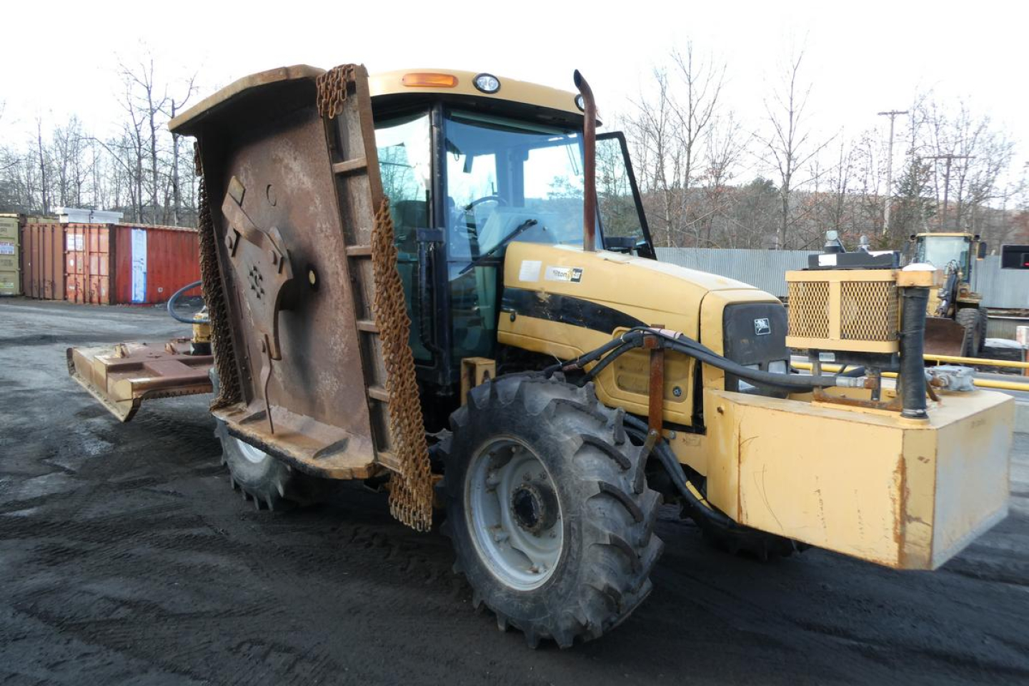 Tractor with front weight bucket and cab, yellow Challenger MT455B showing large ribbed tires and dirty scoop attachment.