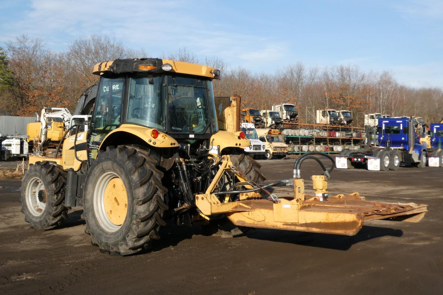 John Deere Challenger MT455B tractor with front-mounted mower/loader attachment in a yard.