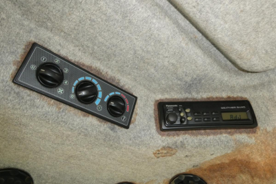 Clutch of HVAC controls and radio panel on tractor cab interior showing knobs and digital display.