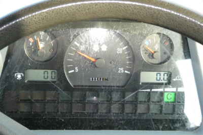 Dashboard of a Challenger MT455B showing analog gauges and digital displays; tachometer centered, left small gauge, right small gauge; various indicator lights and a green square with C.