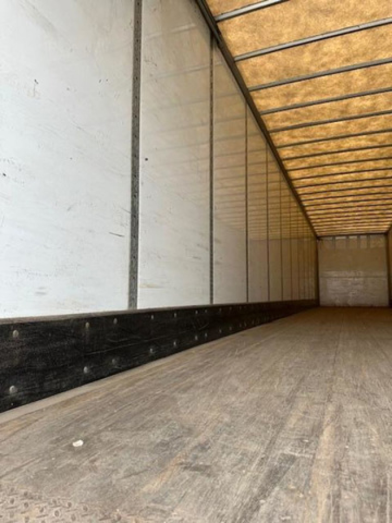 Interior of a trailer with wooden floor and metal side walls; long empty cargo space in a Wabash van.