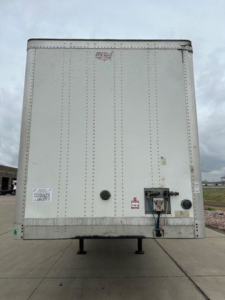 Rear view of a white 2016 Wabash trailer van showing rear doors, mounting feet, and connection components including a circular access port and electrical/air hookups.