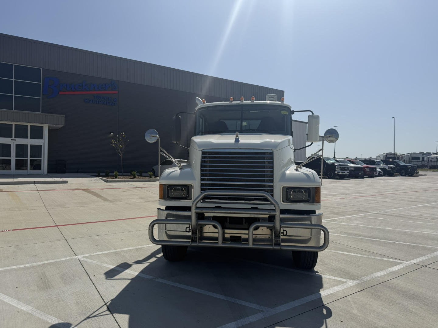 Front view of a white 2020 Mack PI64T conventional daycab truck in a dealership lot showing grille guard and bumper.