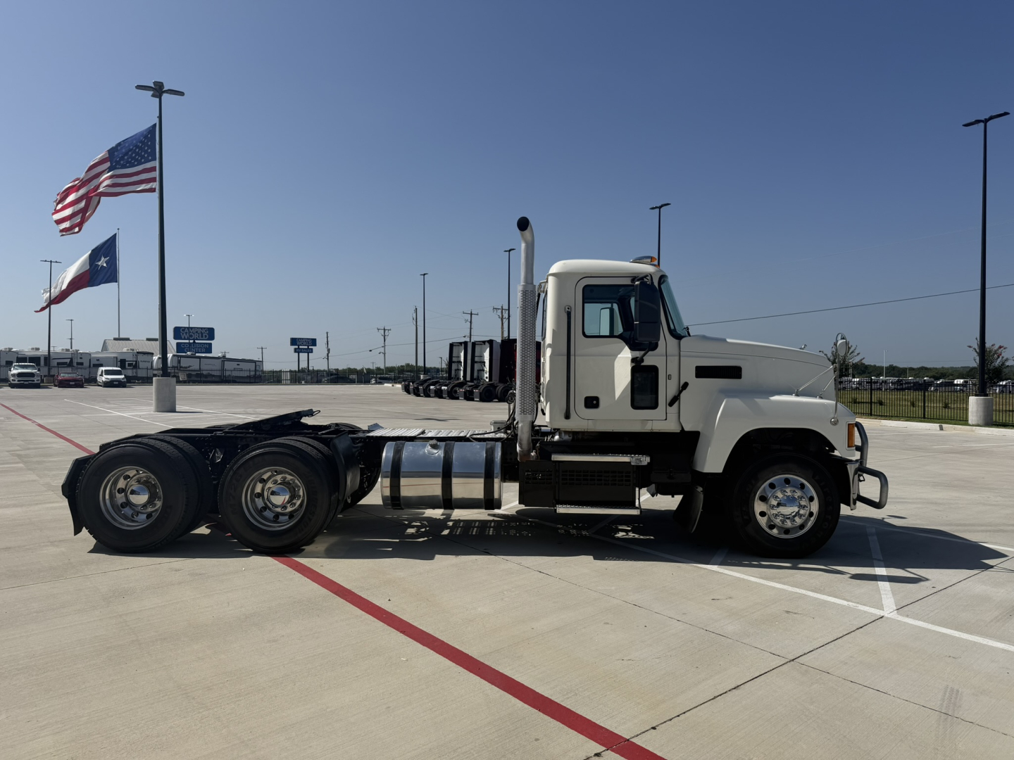 2020 Mack PI64T side view showing truck tractor with white cab and black chassis, long wheelbase, triple rear axles, fuel tanks, exhaust stack, and standard tires.