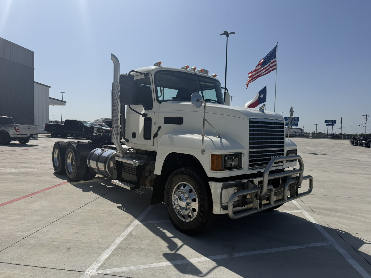 Truck cab in a parking lot with chrome grille guard and dual rear axles. Exterior text not clearly legible.
