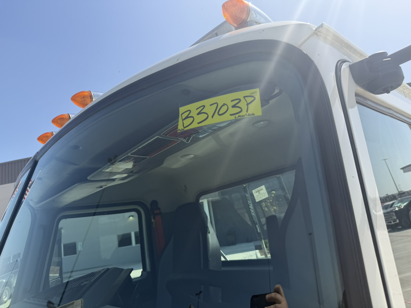 Cab interior of a 2020 Mack PI64T truck with a yellow B3703P stock tag on the windshield and sunlit exterior.