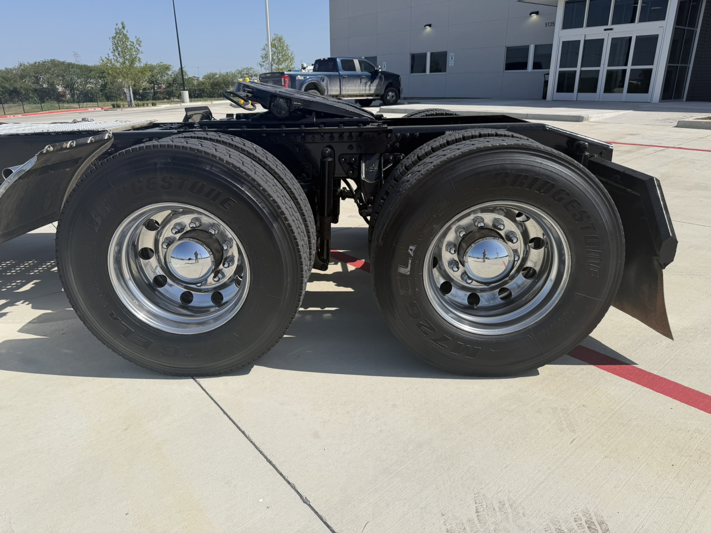 Dual rear wheels of a Mack PI64T tractor showing tires, chrome rims, and part of the chassis frame.