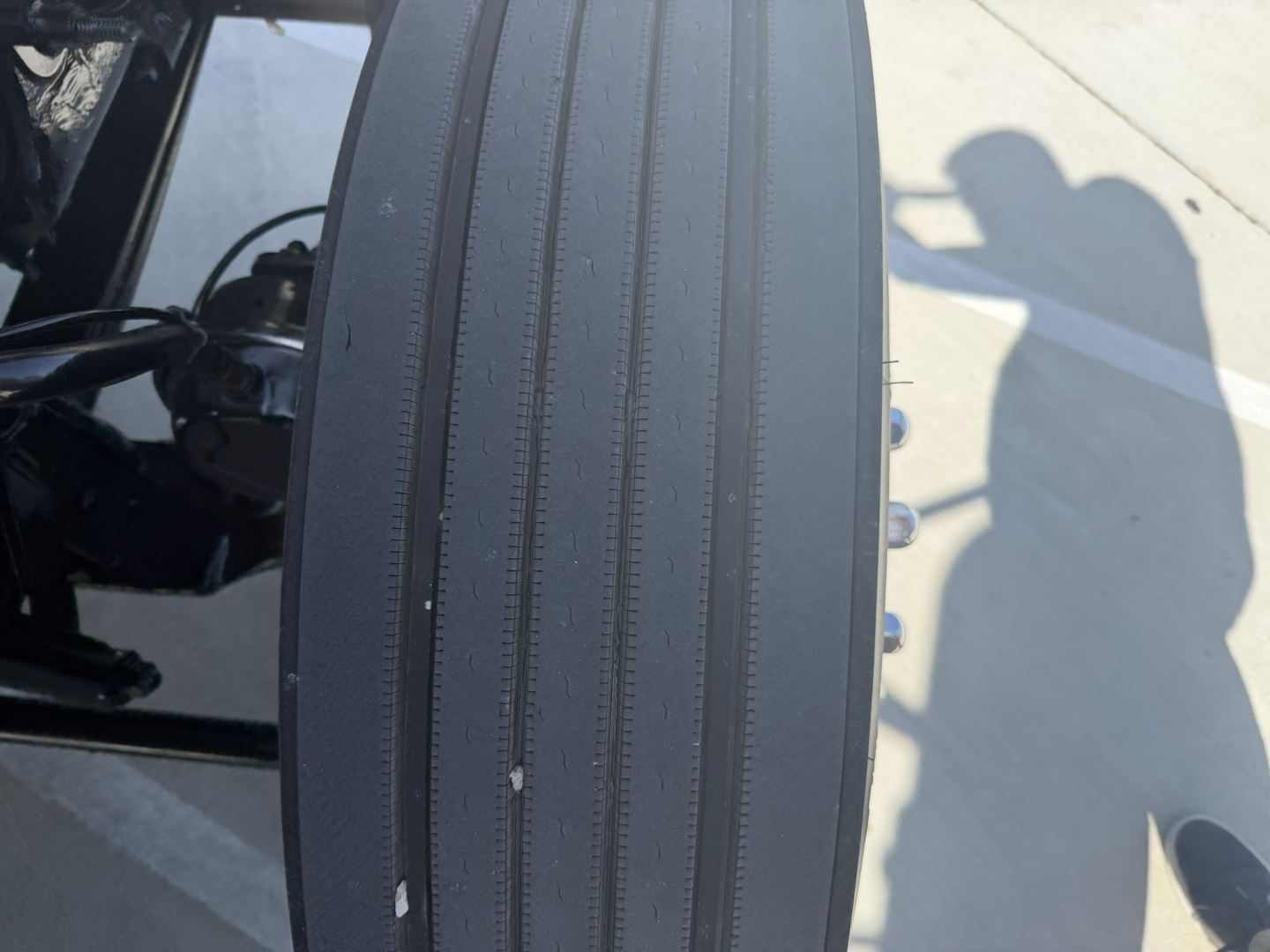 Truck component close-up showing a vertical ribbed surface on a Mack PI64T truck cab or frame area with bolts and shadow of a person