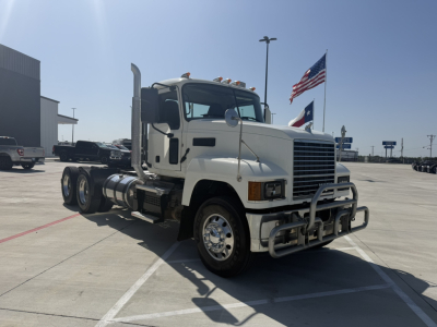 Truck cab in a parking lot with chrome grille guard and dual rear axles. Exterior text not clearly legible.