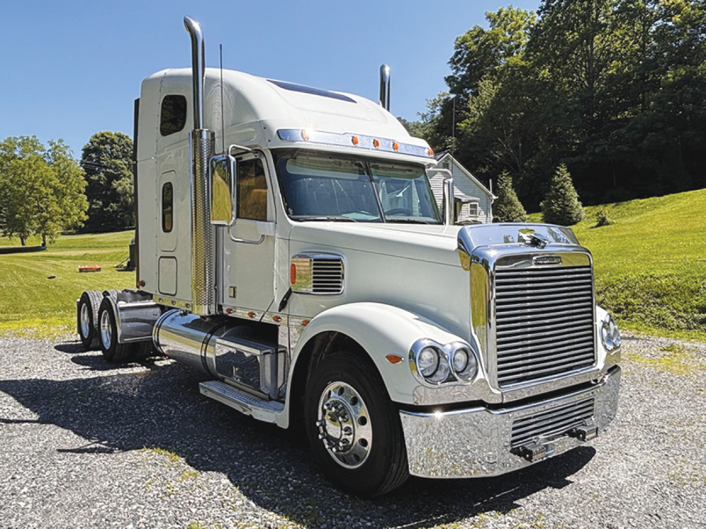 Truck cab: 2018 Freightliner Coronado with chrome grille, dual exhaust stacks, and sleeper cab. Image shows front-left view with chrome bumper and wheels.