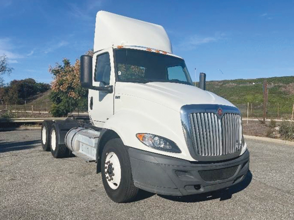 International LT625 truck in white, front-left view showing cab, grille, and dual rear axle chassis.