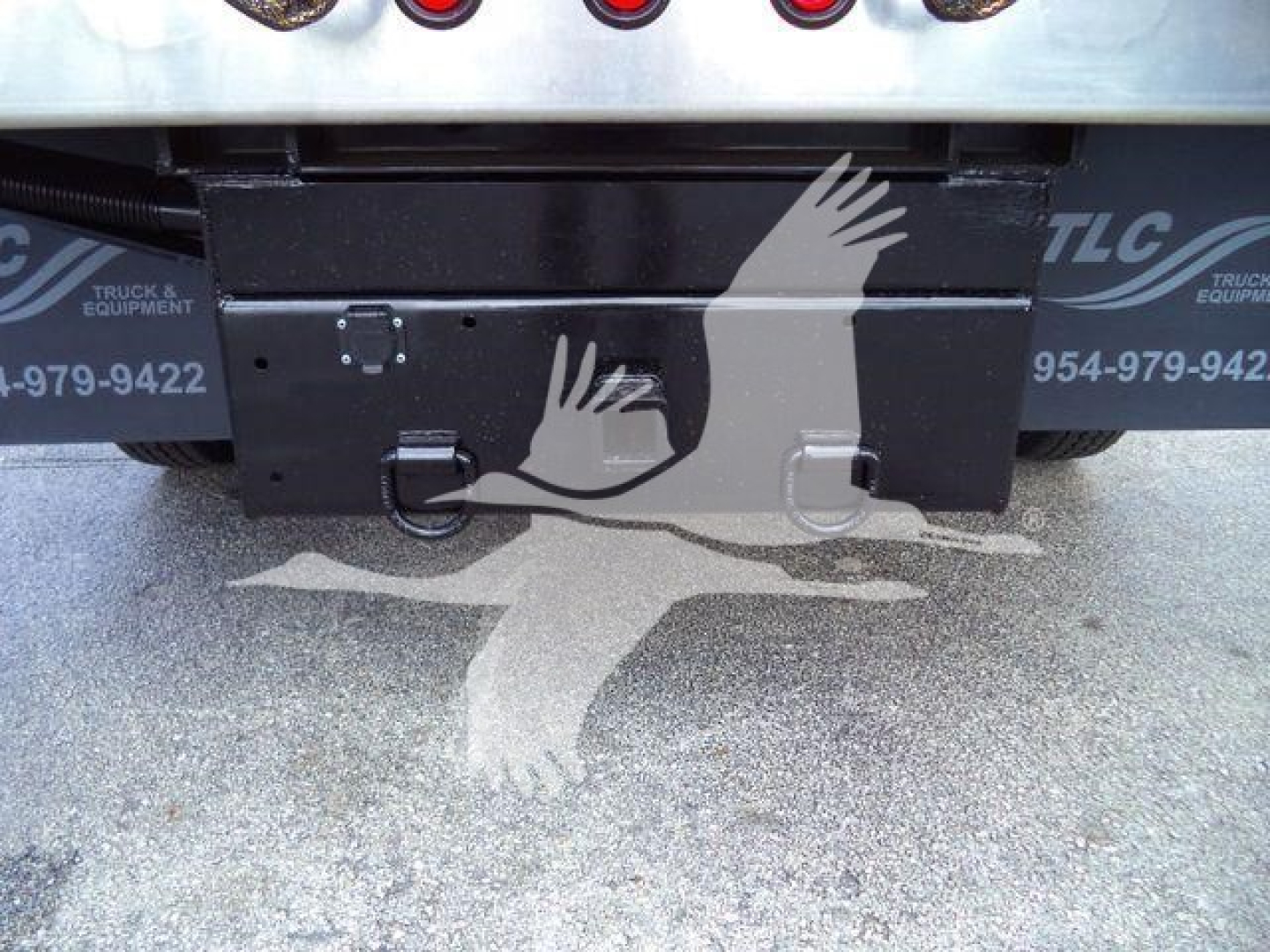 Rear view of 2023 Isuzu NPR HD dump truck showing toolbox and bumper area with tailgate hardware.