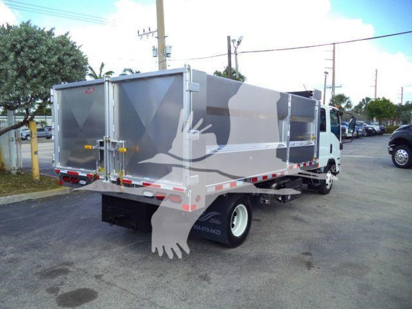 Isuzu NPR HD dump truck in service configuration with aluminum dump body and rear tailgate doors.
