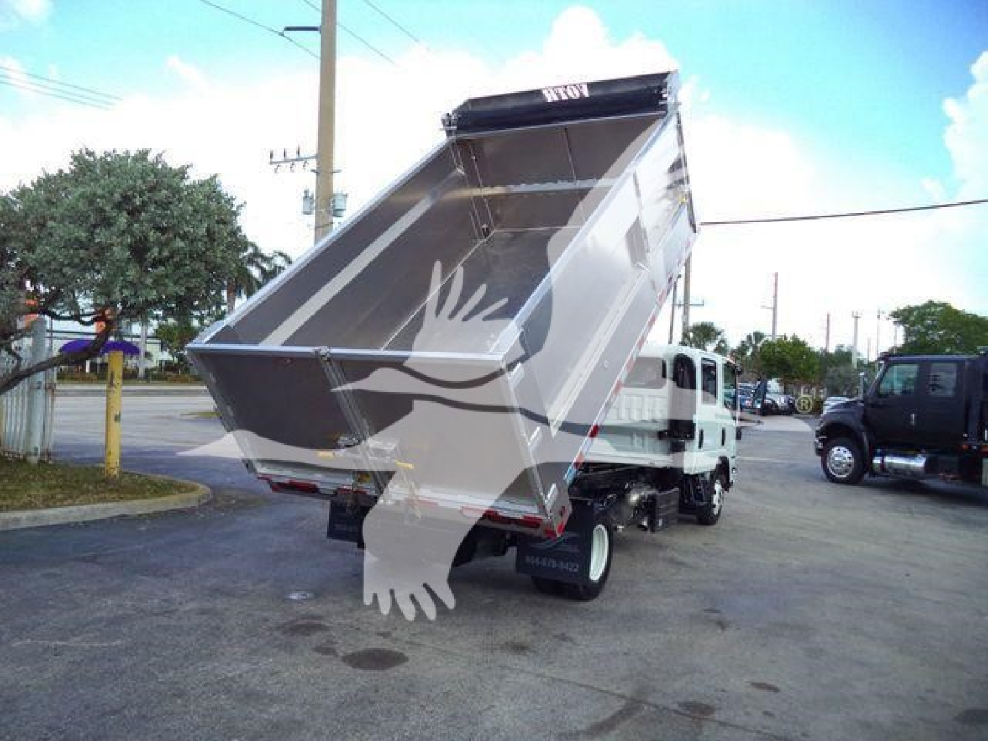 Isuzu NPR-HD dump truck with open bed raised, stock photo showing side view of the dump body and rear wheels.