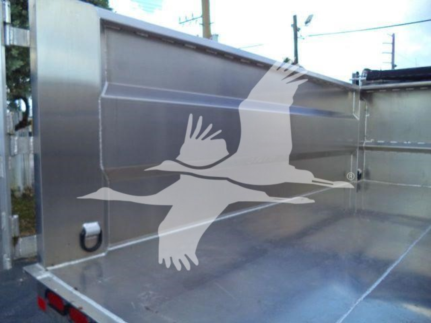Isuzu NPR-HD dump truck bed showing metal side panels and rear corner with a small hinge and stake pocket.