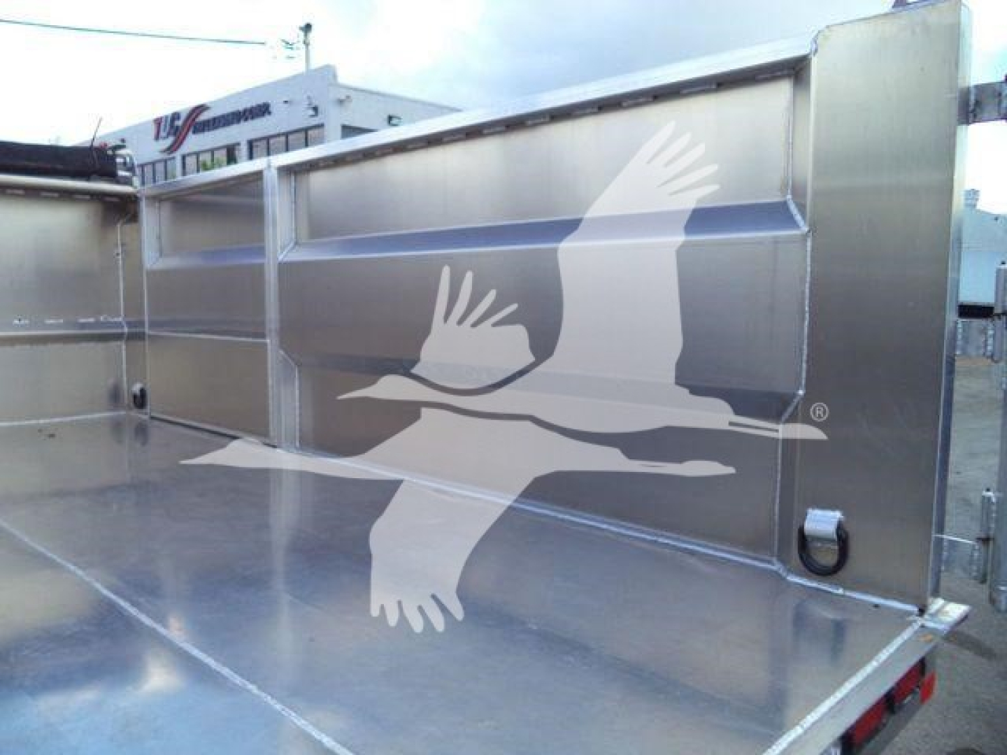 Isuzu NPR-HD dump truck bed with stainless steel side panels and frame, empty bed area visible.