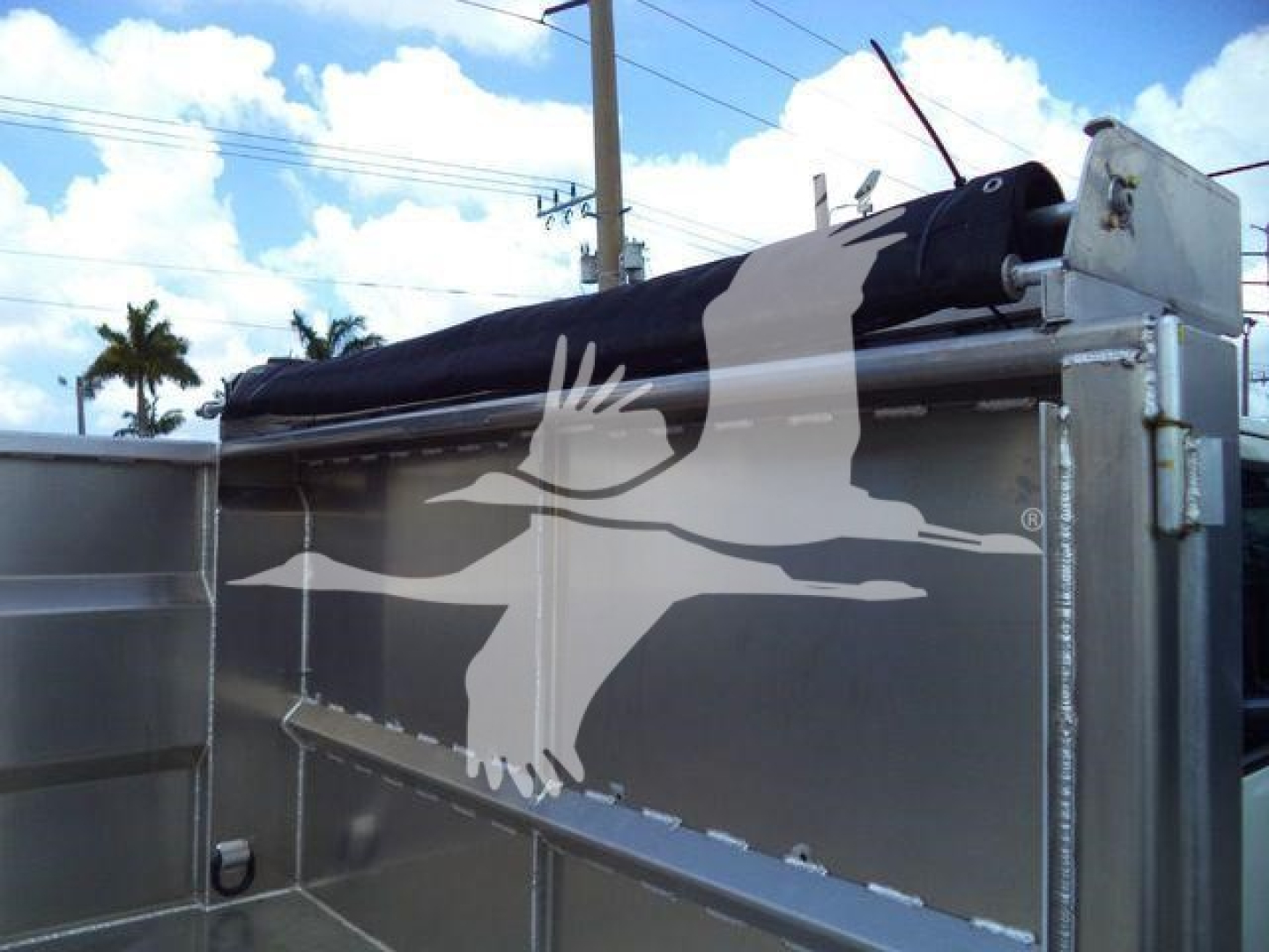 Isuzu NPR HD dump truck bed with hydraulic tailgate and black tarp, aluminum dump body in view.