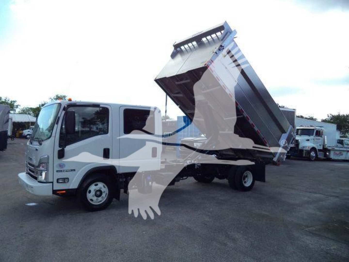 Isuzu NPR HD dump truck in service angle with cargo bed raised, front cab visible, listing for sale.