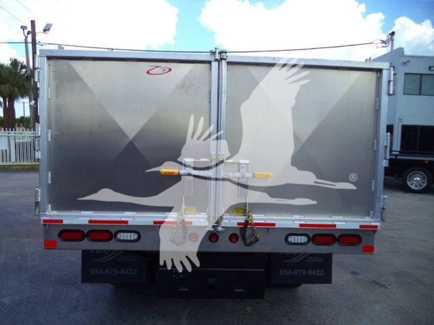 Isuzu NPR HD dump truck rear showing cargo truck bed doors with decals and taillights.