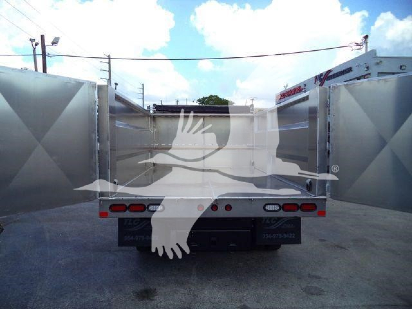 Isuzu NPR-HD dump truck bed viewed from rear with empty cargo bed and taillights visible.