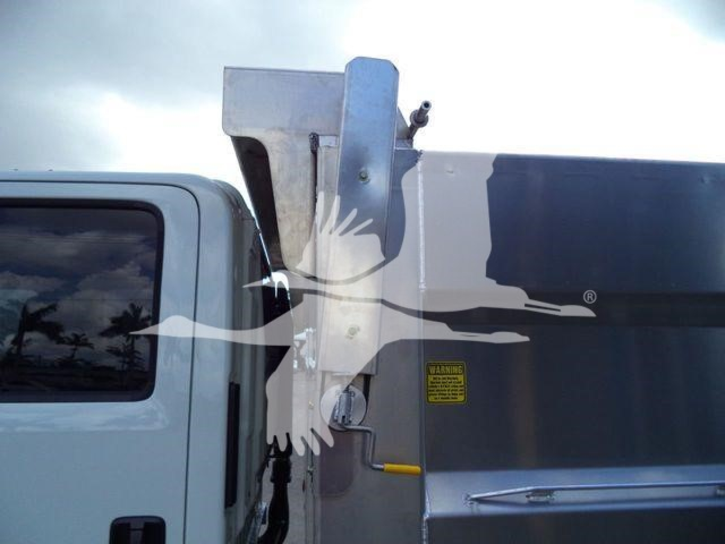 Isuzu NPR HD dump truck side view showing dump body and elevated tailgate with safety decals