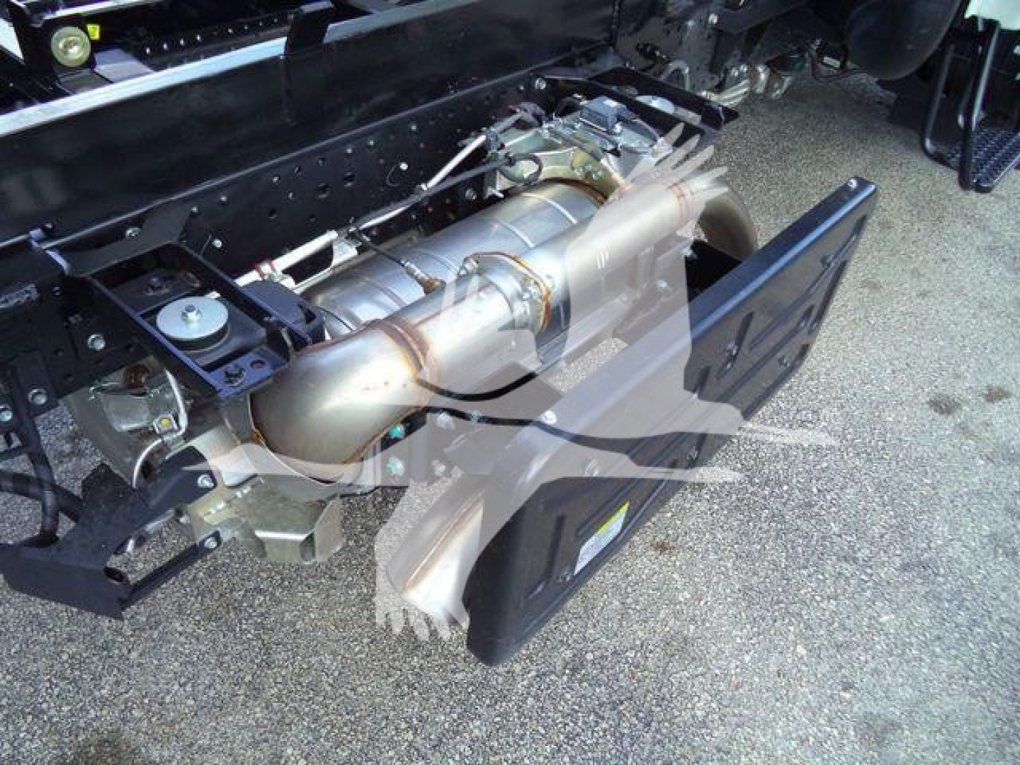 Isuzu NPR-HD engine bay showing exhaust system and chassis components.