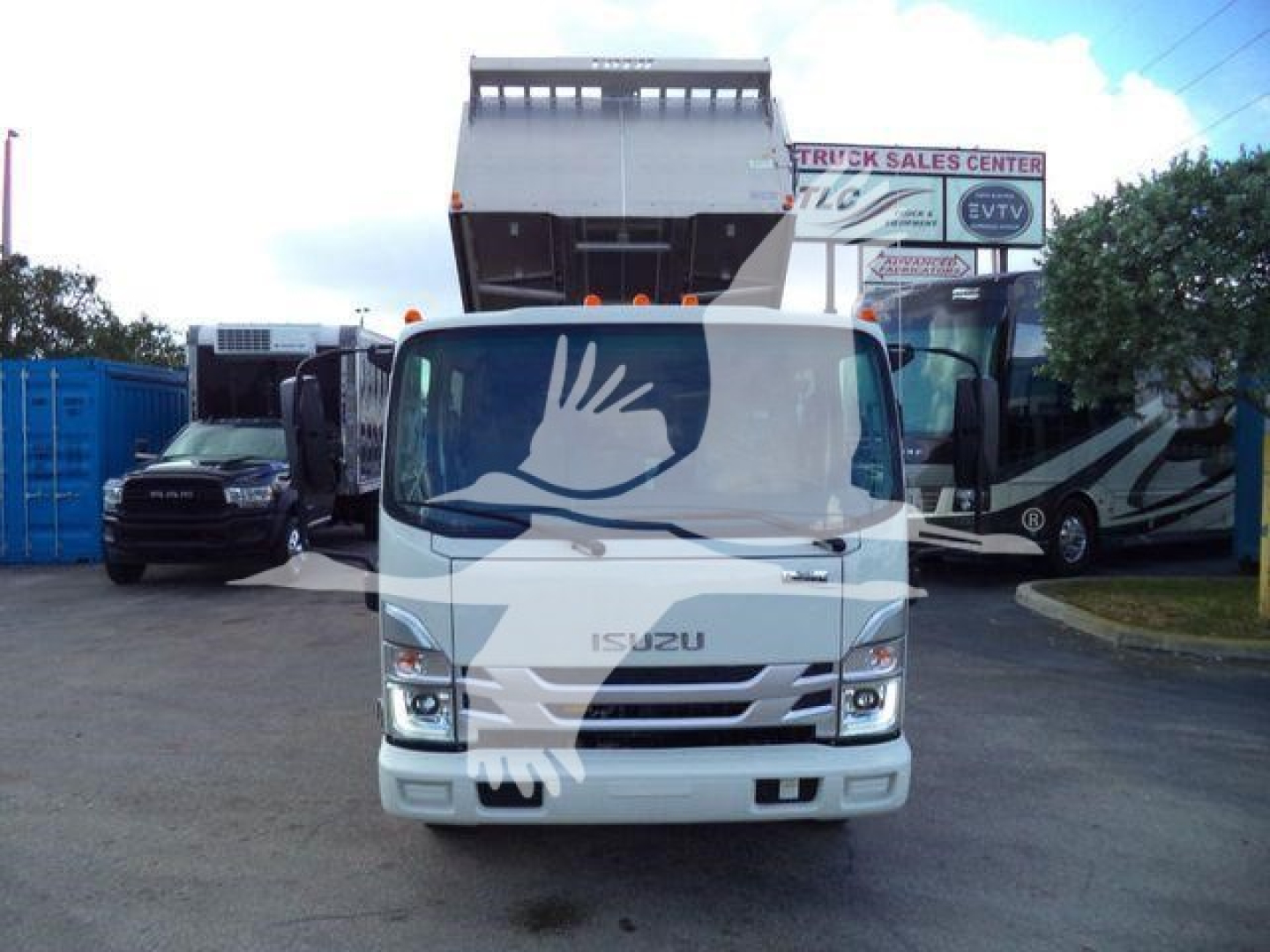 Isuzu NPR Haul truck front view in a dealership lot with dump bed raised.