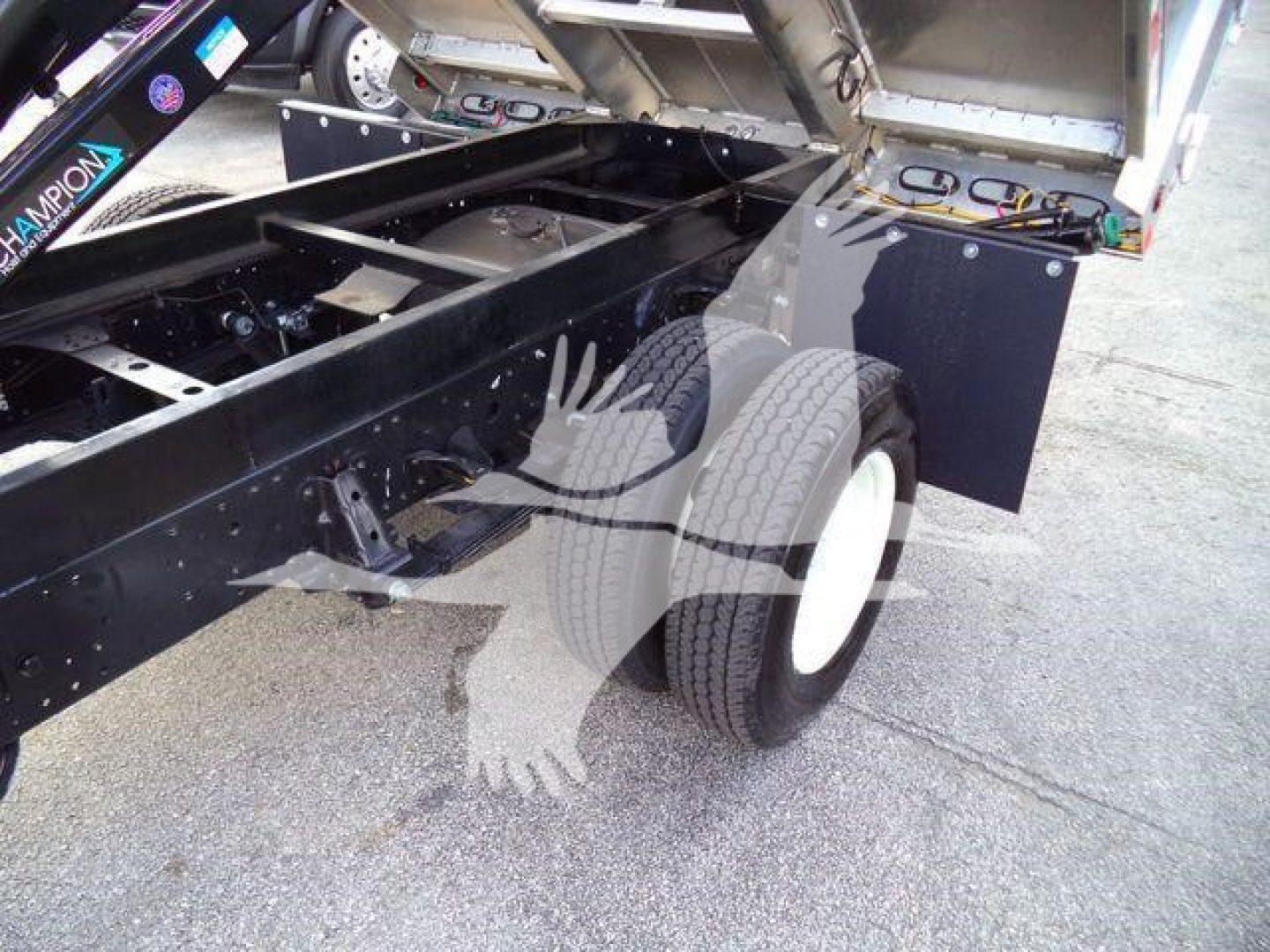 Isuzu NPR-HD dump truck chassis with rear wheels and hydraulic components visible; undercarriage, frame, and bed tilted up showing empty chassis area.