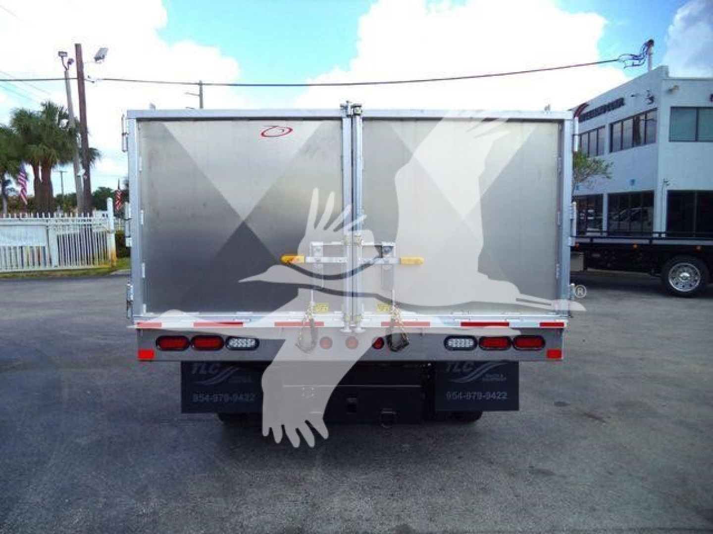 Isuzu NPR-HD dump truck rear view showing dual rear doors, reflective tape, and bumper lights.