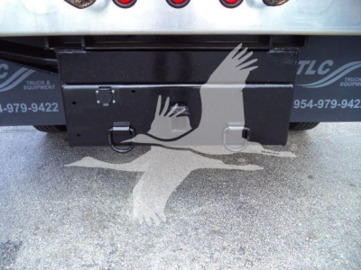 Rear view of 2023 Isuzu NPR HD dump truck showing toolbox and bumper area with tailgate hardware.