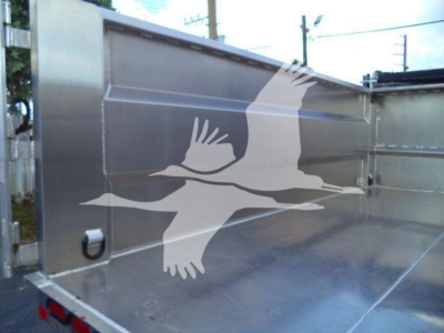 Isuzu NPR-HD dump truck bed showing metal side panels and rear corner with a small hinge and stake pocket.