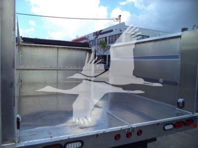 Isuzu NPR HD dump truck bed interior showing aluminum cargo bed with side panels and tail lights visible.