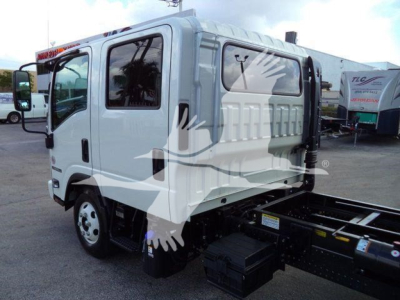 Isuzu NPR-HD dump truck cab with side view showing front grille and empty chassis in yard.