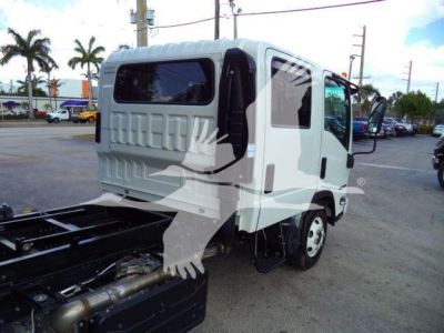 Isuzu NPR HD dump truck cab rear view showing side door and rear window with wiring; white cab, black chassis, front wheel visible.
