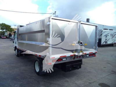 Isuzu NPR HD dump truck in a parking lot, rear and passenger side view showing a silver dump body with rear doors.