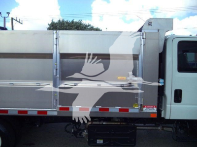 Isuzu NPR HD dump truck side view showing cargo bed with metal panels and reflective tape