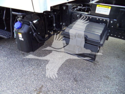Isuzu NPR near-side frame with auxiliary battery box and air tank visible under truck, with black plastic tool/box and mounting hardware.