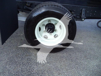 Isuzu NPR-HD dump truck wheel and tire, white steel wheel mounted on black truck frame; visible lug nuts and hub with central black cap.