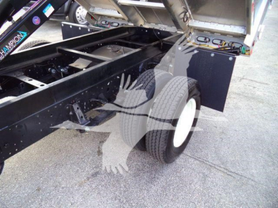 Isuzu NPR-HD dump truck chassis with rear wheels and hydraulic components visible; undercarriage, frame, and bed tilted up showing empty chassis area.