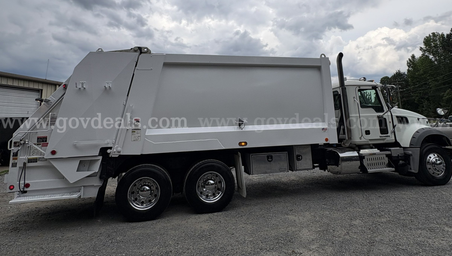 Mack GU713 2015 garbage truck side view showing dump body and chassis with 6 wheels.
