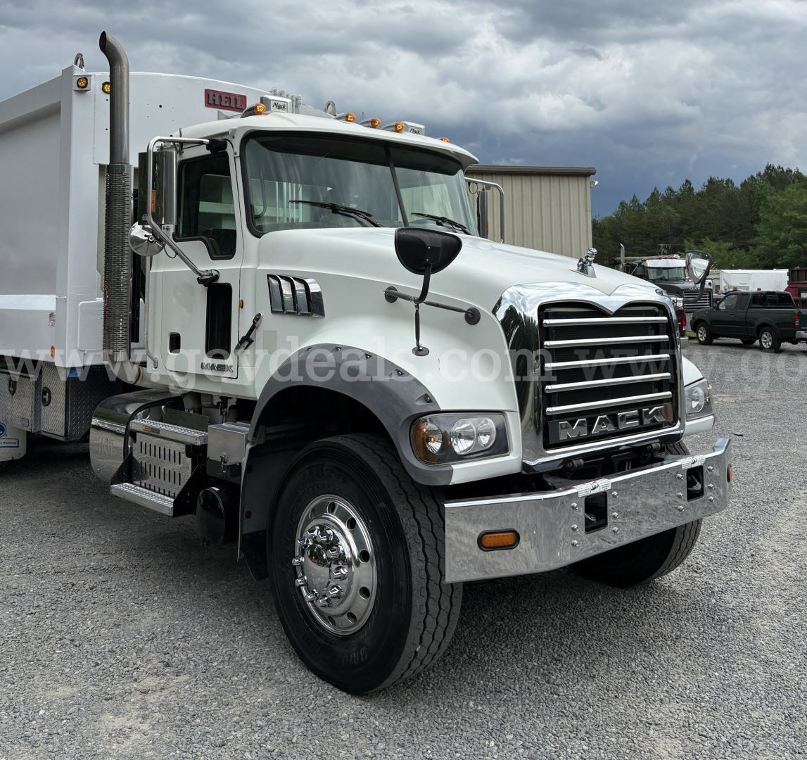Mack GU713 truck in a yard showing front grille and bumper with chrome accents and dual mirrors.