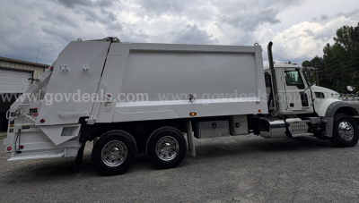 Mack GU713 2015 garbage truck side view showing dump body and chassis with 6 wheels.