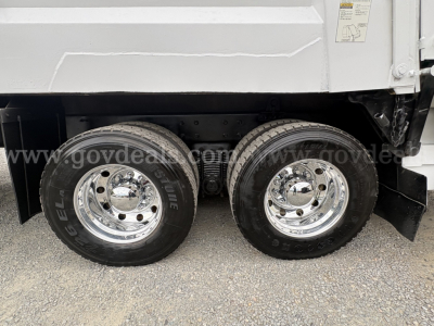 Dual rear wheels of a Mack GU713 dump truck with chrome rims and black tires.