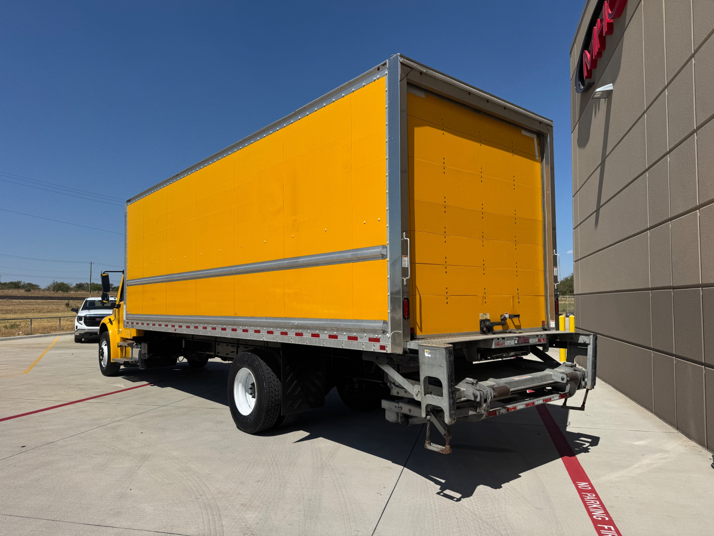 Truck with yellow box body showing rear cargo area and bumper. Text not clearly visible on side; no legible labels or fluid reservoirs visible in this view.