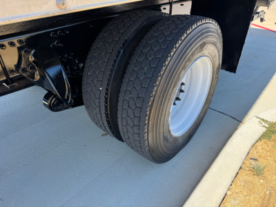 Fleet chassis with dual rear wheels and black frame showing Freightliner M2-106 undercarriage and tire tread.